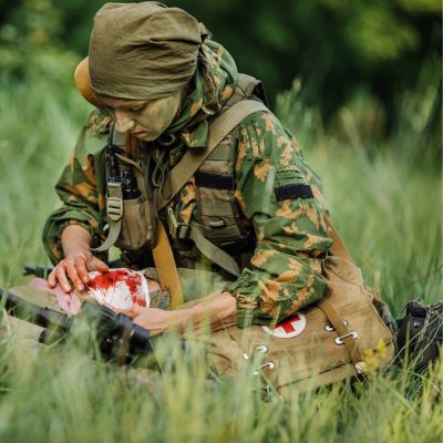Military personnel applying wound dressing to wounded in the field.